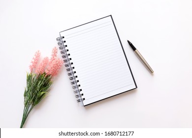 Flat Lay Of Notebook, Pen And Flower On White Background