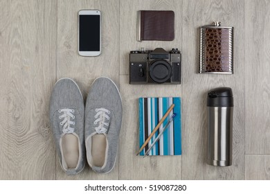 Flat lay of objects for traveler. young woman or man. Overhead view of Traveler's accessories for modern young person. Different objects on wooden background.