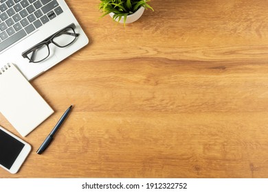 Flat lay of Office desk with laptop, and blank notepad with a coffee cup and smart phone on wood table, copy space, top view - Powered by Shutterstock