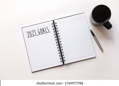 Flat Lay Of Open Notebook With Words Written - 2021 Goals. Coffee, Pen On White Background. New Year Resolution