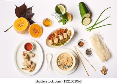 Flat lay of oriental dinner from soup with seeds, tempura shrimps and noodles with vegetables preparing for client. Three dishes lunch with mint tea ready for eating on white tablecloth. - Powered by Shutterstock