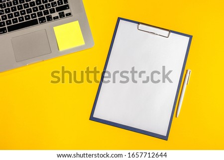 Flat lay out. Computer on yellow background with paper folio, pen and sticky notes. Business concept idea. Copy space.