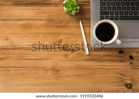 Flat lay overhead above close up view photo of laptop notebook with cup of beverage pen and green succulent isolated brown backdrop with blank empty space