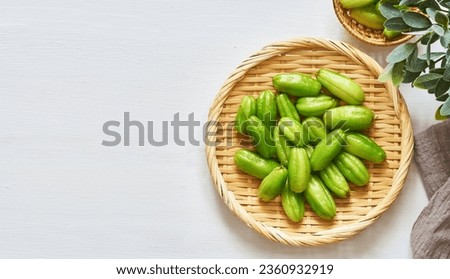flat lay overhead top view green bilimbi kamias fruit in bamboo plate on white wood table background. green bilimbi kamias on white background. green bilimbi kamias white food table light mood      