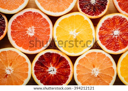 Flat lay, overhead view of different color grapefruits and citrus fruit arranged artistically on a wooden table.