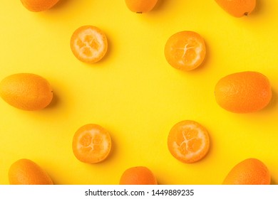 Flat lay pattern of fresh kumquats on a yellow background. Top view, kumquats mock-up