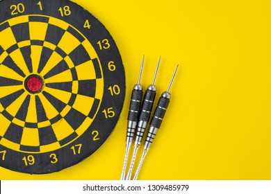 Flat Lay Of Perfect Black Darts With Dartboard On Solid Yellow Background With Copy Space Using As Target And Goals Or Three Best Important Things You Need To Know Concept.