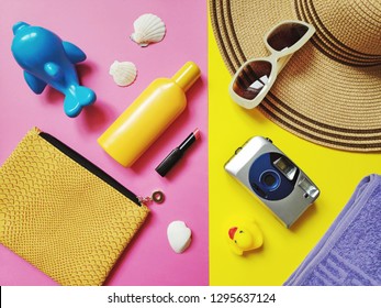 Flat Lay Photo Beach Essentials. Top View Cosmetic Bag, Sunscreen Bottle, Sun Hat, Sunglasses And Camera