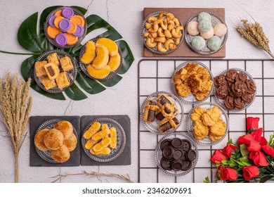 flat lay photo a bunch cookies on a leaf, wooden plate, black rock plate, glass plate and cooling rack with flower on the corner. kue lebaran for celebrate eid fitr after ramadhan. - Powered by Shutterstock
