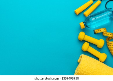 flat lay photo of fitness equipment over turquoise blue backgound. top view of yellow street workout objects. yellow fitness objects on the blue background with some copy space