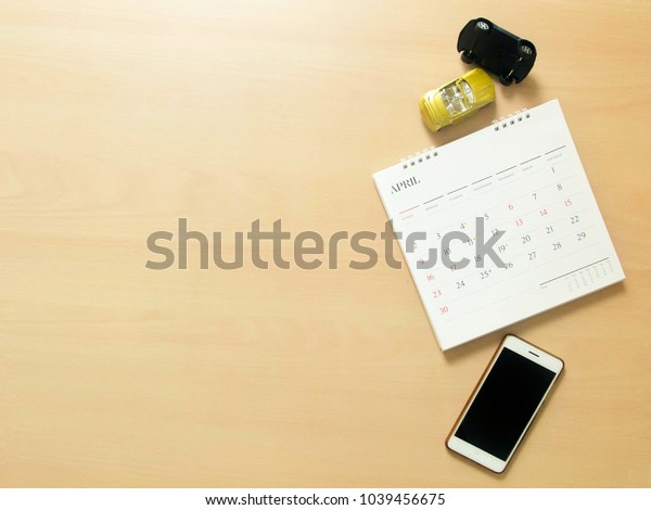 Flat lay\
photo of mobile, calendar and two model cars are demonstrated\
crashing on wood background with copy\
space.