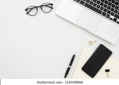 Flat lay photo of office desk with laptop, smartphone, eyeglasses and notebook with copy space background. Mockup - Shutterstock ID 1145540066