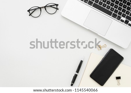 Flat lay photo of office desk with laptop, smartphone, eyeglasses and notebook with copy space background. Mockup