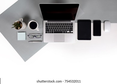 Flat lay photo of Office table with laptop computer, notebook, digital tablet, mobile phone, Pencil, eyeglasses  on modern two tone (white and grey) background. Desktop office mockup concept.