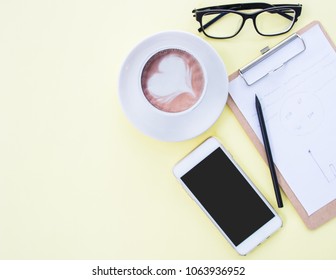Flat lay photo of workspace desk with smartphone, eyeglasses and clipboard on colorful background with copy space.