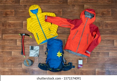 Flat lay photograph of climbing, trekking and hiking gear and equipment. Jacket, backpack, outdoor pants and other apparel. Outdoor equipment on wooden floor. - Powered by Shutterstock