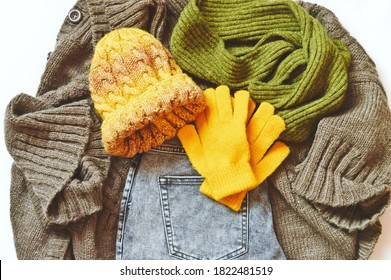 Flat Lay Photography Fall And Winter Fashion Clothes. Brown Cardigan, Gray Jeans, Yellow Hat, Gloves And Green Woolen Scarf. Top View Photo Autumn Wardrobe Items