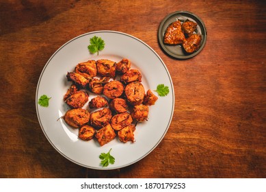 Flat lay of pickle flavoured spicy soya nuggets presented beautifully on a white plate with wooden background. High protein vegetarian food made from soya bean cooked as an indian appetizer.