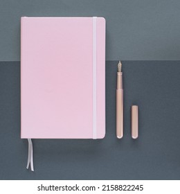 A flat lay of a pink notepad and an open pen