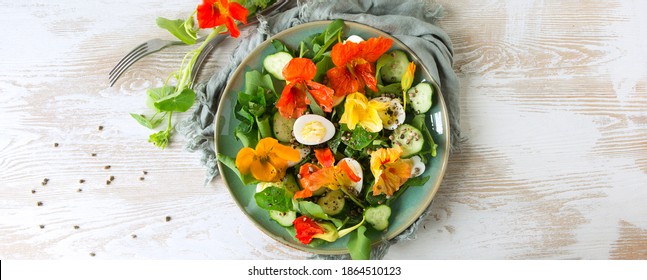 flat lay plate of salad with eggs, cucumbers and edible nasturtium flowers on light wooden table, space for text - Powered by Shutterstock