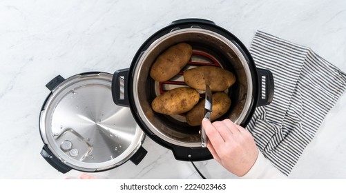 Flat lay. Pressure Cooker Baked Potatoes. Poking cooked potatoes with a knife to prepare baked potatoes. - Shutterstock ID 2224023463