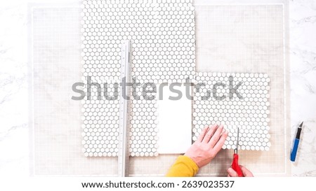 Flat lay. In the process of mounting peel and stick mosaic tiles onto a foam board, perfect for enhancing a food photography studio's aesthetic.