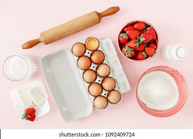 Flat lay raw ingredients for cooking strawberry pie or cake on pink background  (eggs, flour, milk, sugar, strawberry), top view. Bakery background. Recipe for strawberry pie