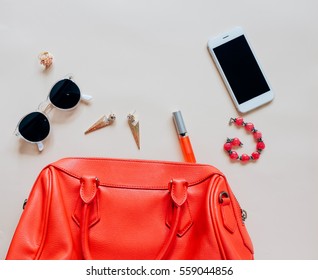 Flat Lay Of Red Leather Woman Bag Open Out With Cosmetics, Accessories And Smartphone On Yellow Background