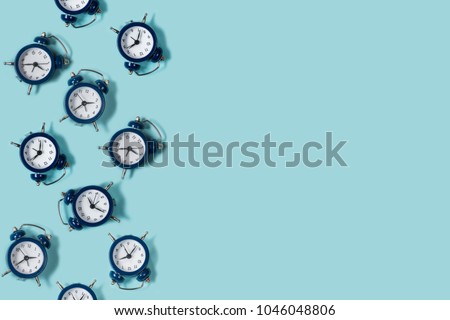 Flat lay retro beautiful new alarm clock on blue color background. Pattern. Copy space