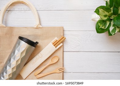 Flat Lay Of Reuse Accessories Compose Of Travel Mug, Wooden Fork ,spoon ,reusable Straw ,cloth Bag  And Tree, On White Wooden Background, Reusable  And Go Green , Eco Friendly With Zero Waste Concept