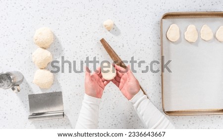 Flat lay. Rolling bread dough with a french rolling pin to bake naan dippers.