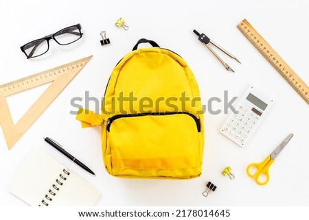 Flat lay of school backpack with school items and student accessories, top view.