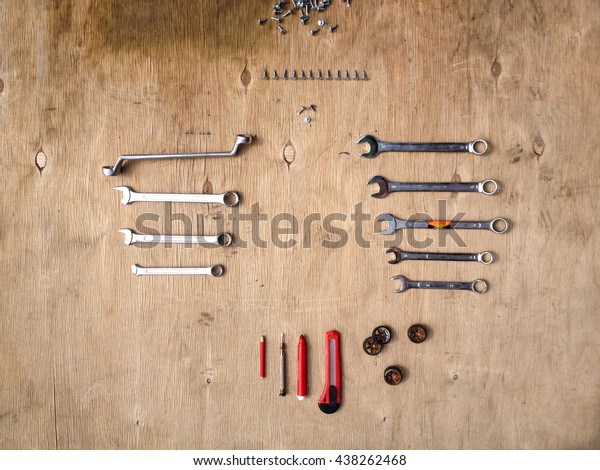 Flat lay of set of tools for car repairing such as\
wrenches on wooden background with contrast red pens and knife. Top\
view.
