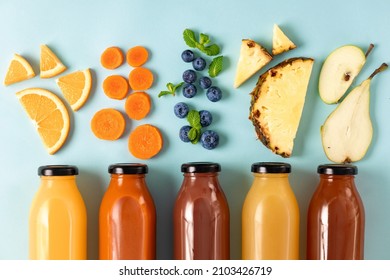 Flat lay set of various fresh juices from fruit, berries and vegetables in bottles on blue background, top view. Healthy eating concept