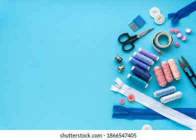 Flat lay of sewing accessories. Threads and tailoring tools on blue background, space for text