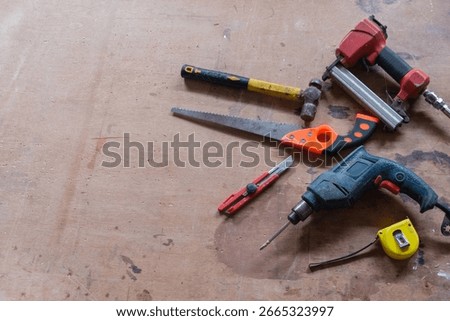 A flat lay shot of various hand tools for woodworking and home improvement, arranged on a rustic wooden workbench. The image captures the essence of DIY projects and craftsmanship.