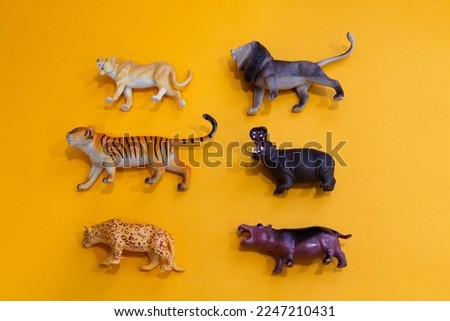 Flat lay side view of small toys in the shape of African animals set on plain orange background