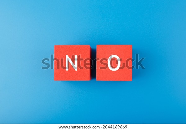 Flat lay with single word no on red\
cubes against blue background. Say no to violence, toxic people,\
discrimination, agism and other negative\
factors