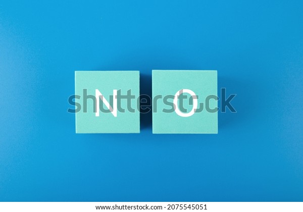 Flat lay with single word no on blue\
cubes against blue background. Say no to violence, toxic people,\
discrimination, agism and other negative\
factors
