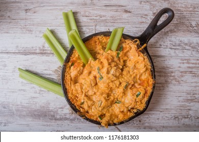 Flat lay of a skillet with spicy buffalo chicken cheese dip with celery