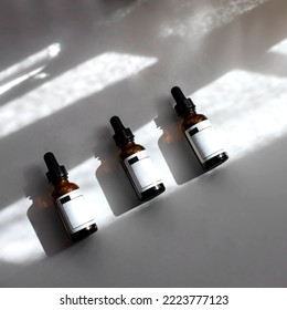 Flat lay of skin care routine , three dropper bottles with pipette and mocke up label on white background with hard light and shadow.