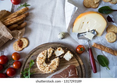 Flat lay with snacks.Two types of cheese, bread sticks, crackers, prosciutto, cherry tomatoes, cranberry sauce and herbs on neutral background.