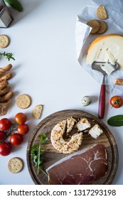 Flat lay with snacks.Two types of cheese, bread sticks, crackers, prosciutto, cherry tomatoes, cranberry sauce and herbs on neutral background.