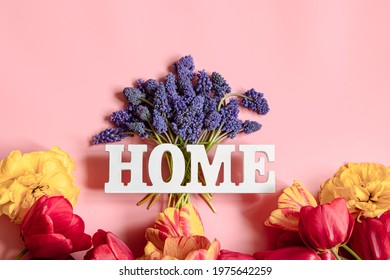 Flat lay spring composition with bright flowers and the decorative word home.