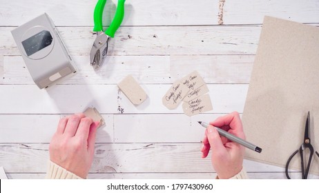 Flat lay. Step by step. Labeling brown paper gift tags with a black marker.