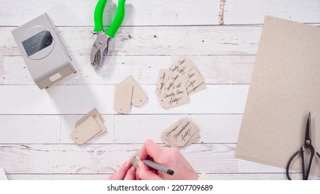 Flat Lay. Step By Step. Labeling Brown Paper Gift Tags With A Black Marker.