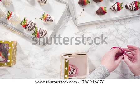 Flat lay. Step by step. Packaging chocolate dipped strawberries into a paper box for a gift.