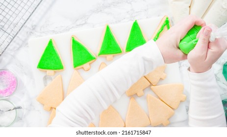 Flat lay. Stp by step. Icing Christmas tree-shaped sugar cookies with green royal icing.