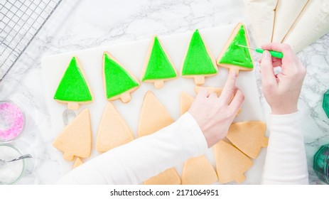 Flat lay. Stp by step. Icing Christmas tree-shaped sugar cookies with green royal icing.
