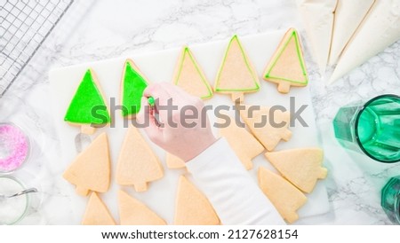 Flat lay. Stp by step. Icing Christmas tree-shaped sugar cookies with green royal icing.